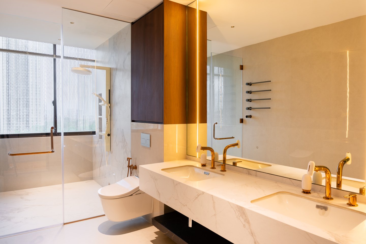 Floating vanity in white marble with brushed brass taps and a wall-hung toilet in a Kuala Lumpur condominium bathroom