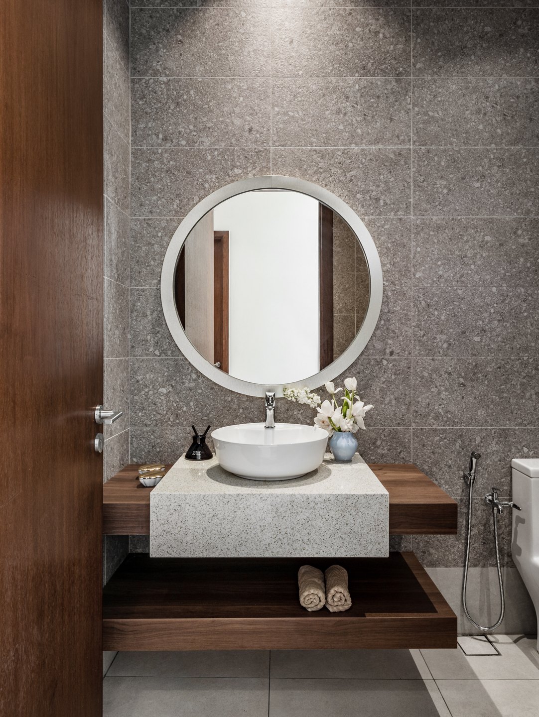 Powder room design with a vessel sink on a stone slab and a round mirror against textured tile, Kelana Jaya bungalow