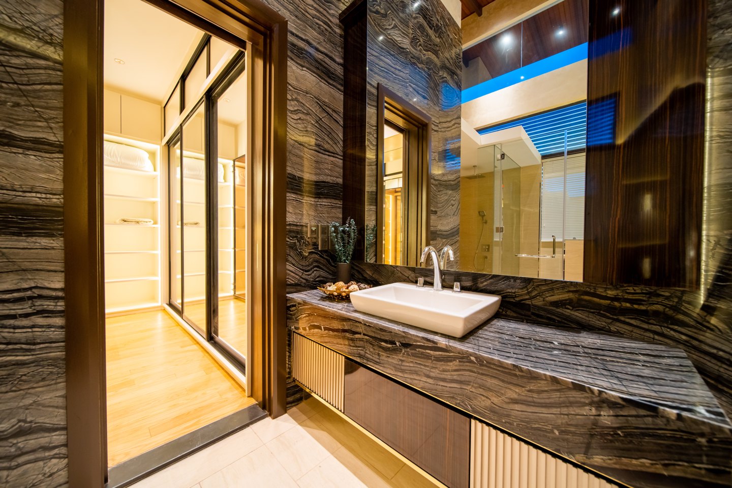 Bathroom feature wall in striated dark stone running from the shower wall across the vanity, second suite of a Bangsar bungalow