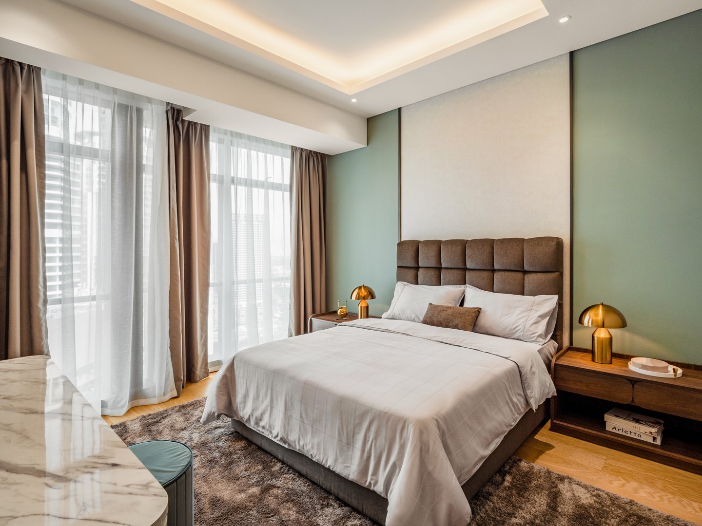 Cool-toned bedroom colour palette — sage green wall with grey upholstered bed in a Kuala Lumpur condominium