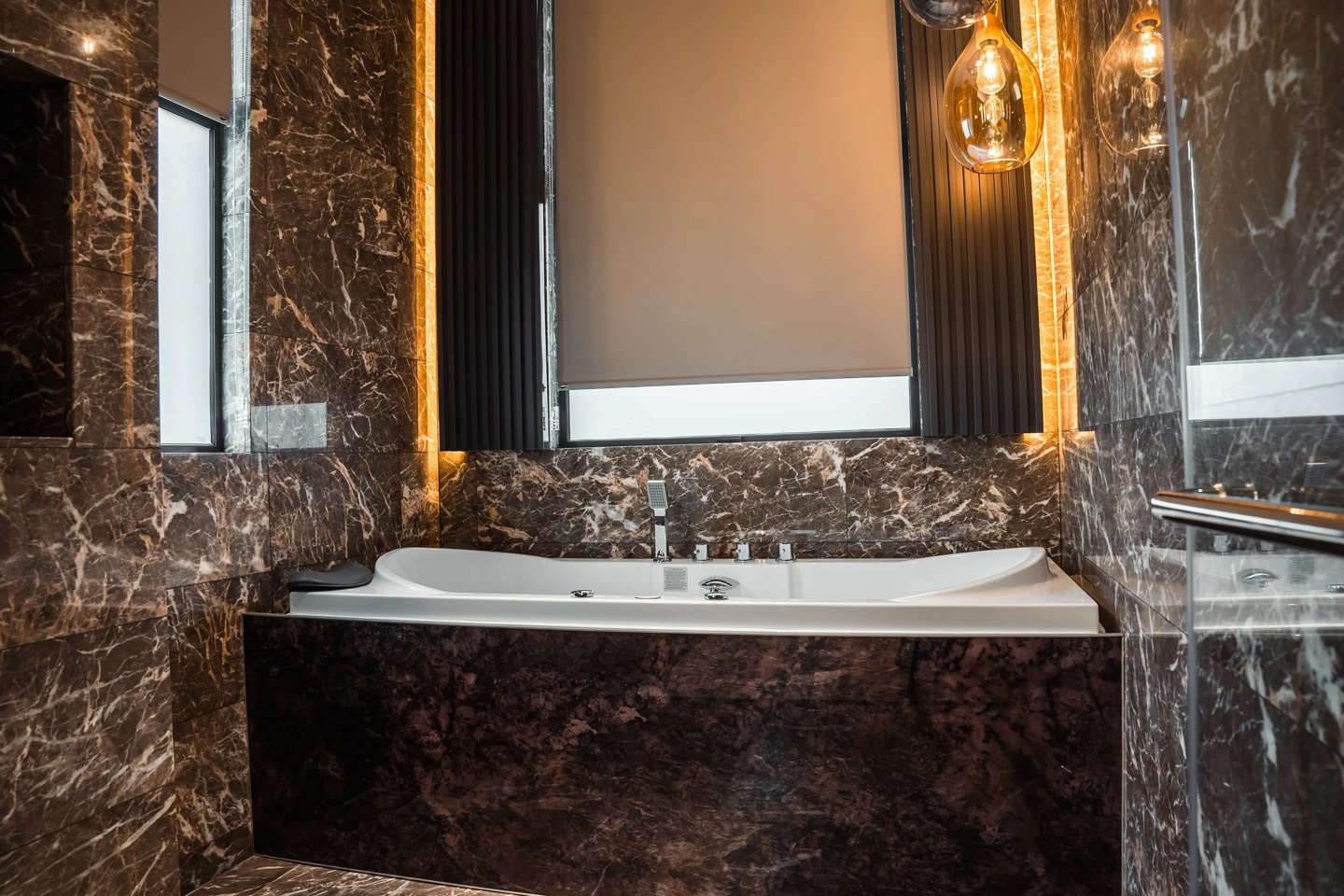 Warm brown marble bathtub surround and walls with concealed lighting in a Cyberjaya master bathroom, Setia Marina One