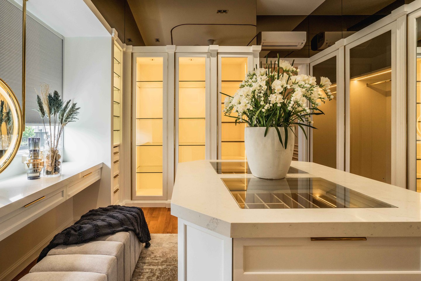 Walk-in wardrobe with glass-fronted cabinets and lit shelving in a Malaysian home, EcoSpring
