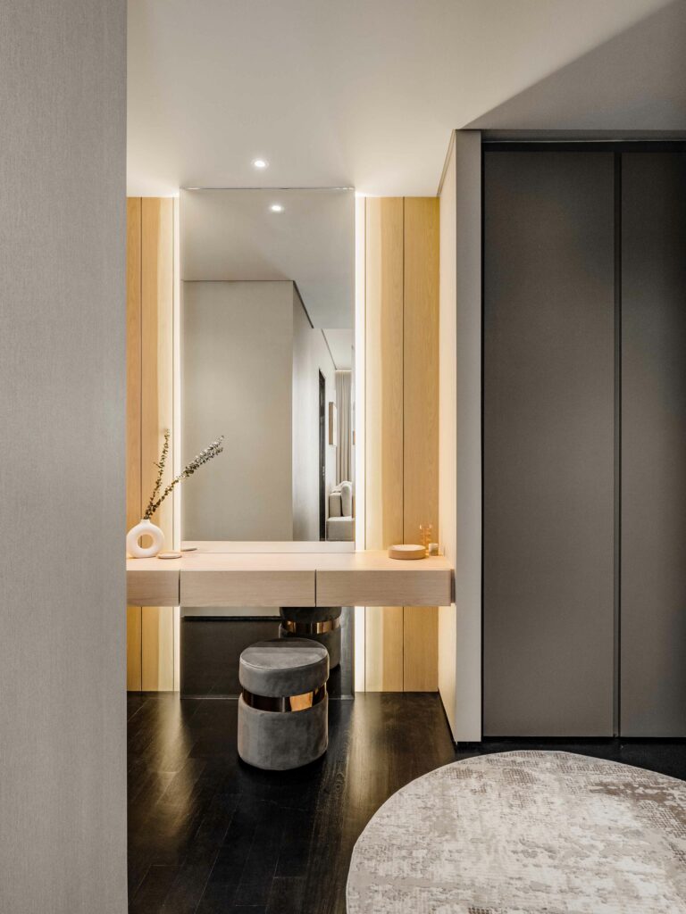 Step into luxury with this custom-designed dressing area featuring a stunning backlit mirror and a comfortable, stylishly designed stool.
