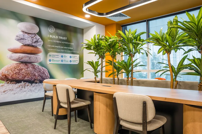 Persada PLUS Office, Petaling Jaya: collaboration table with planters and a company values wall