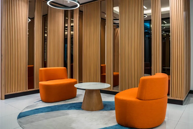 Persada PLUS Office, Petaling Jaya: waiting area with timber slat screens and orange swivel chairs