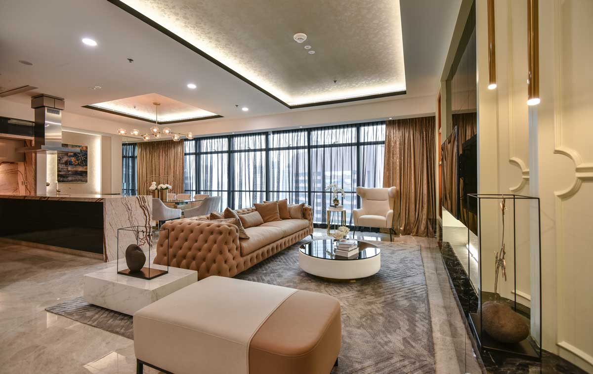 A stunning living room in the Ritz Carlton Residence, designed by Blaine Robert Design in Malaysia. The room exudes luxury and sophistication with its plush sofas, ornate decor, and warm color scheme. The space is beautifully lit, highlighting the intricate details of the interior design. This image showcases the company's expertise in luxury residential interior design.