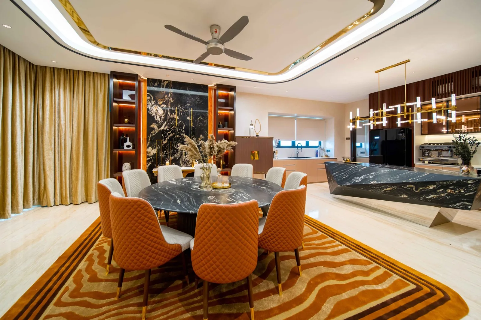 Curved cove ceiling with a ceiling fan and linear chandelier over a round dining table in the Bangsar bungalow