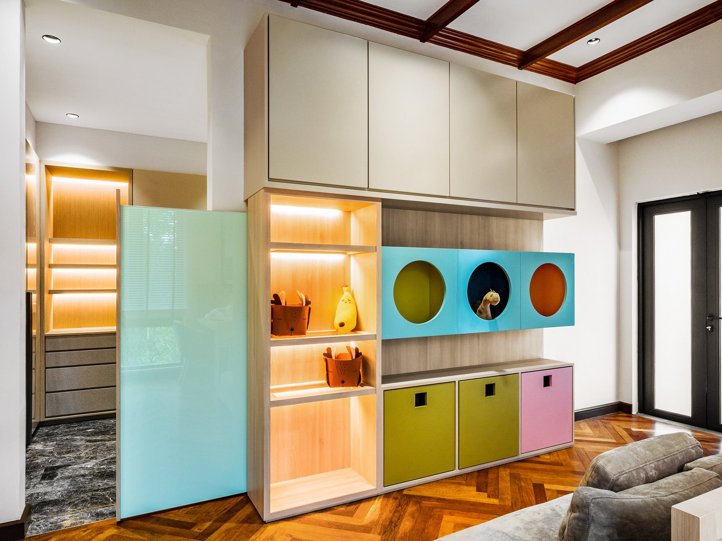 Colour-blocked storage feature wall with circular display niches in a Malaysian family home
