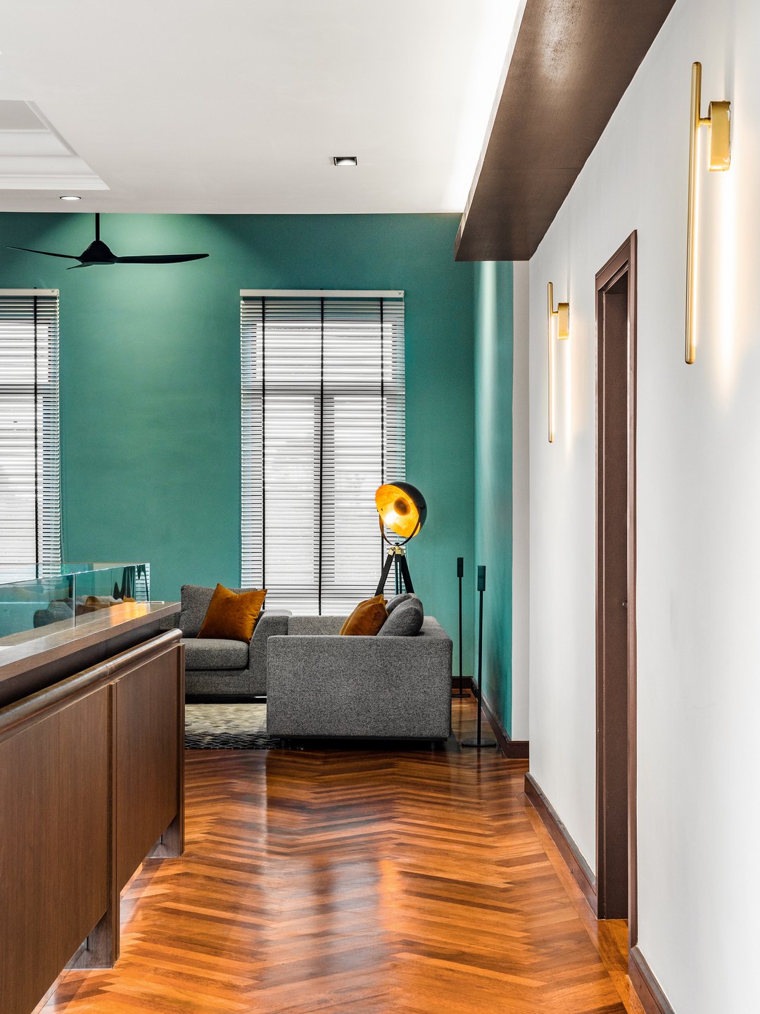 Deep teal painted feature wall rising through a double-volume space in a Malaysian bungalow