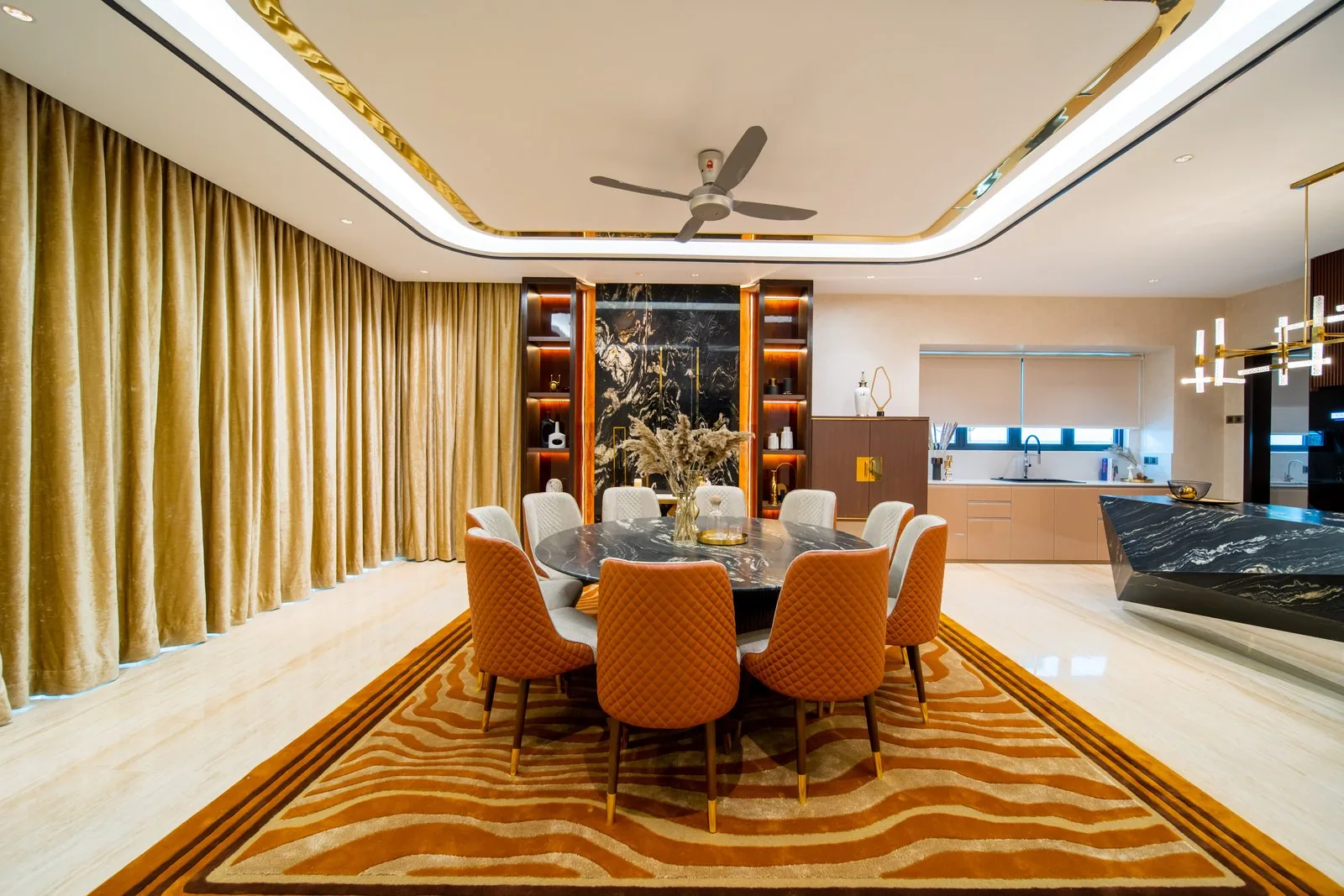 Large round dining table with quilted orange chairs on a patterned rug in a Bangsar bungalow