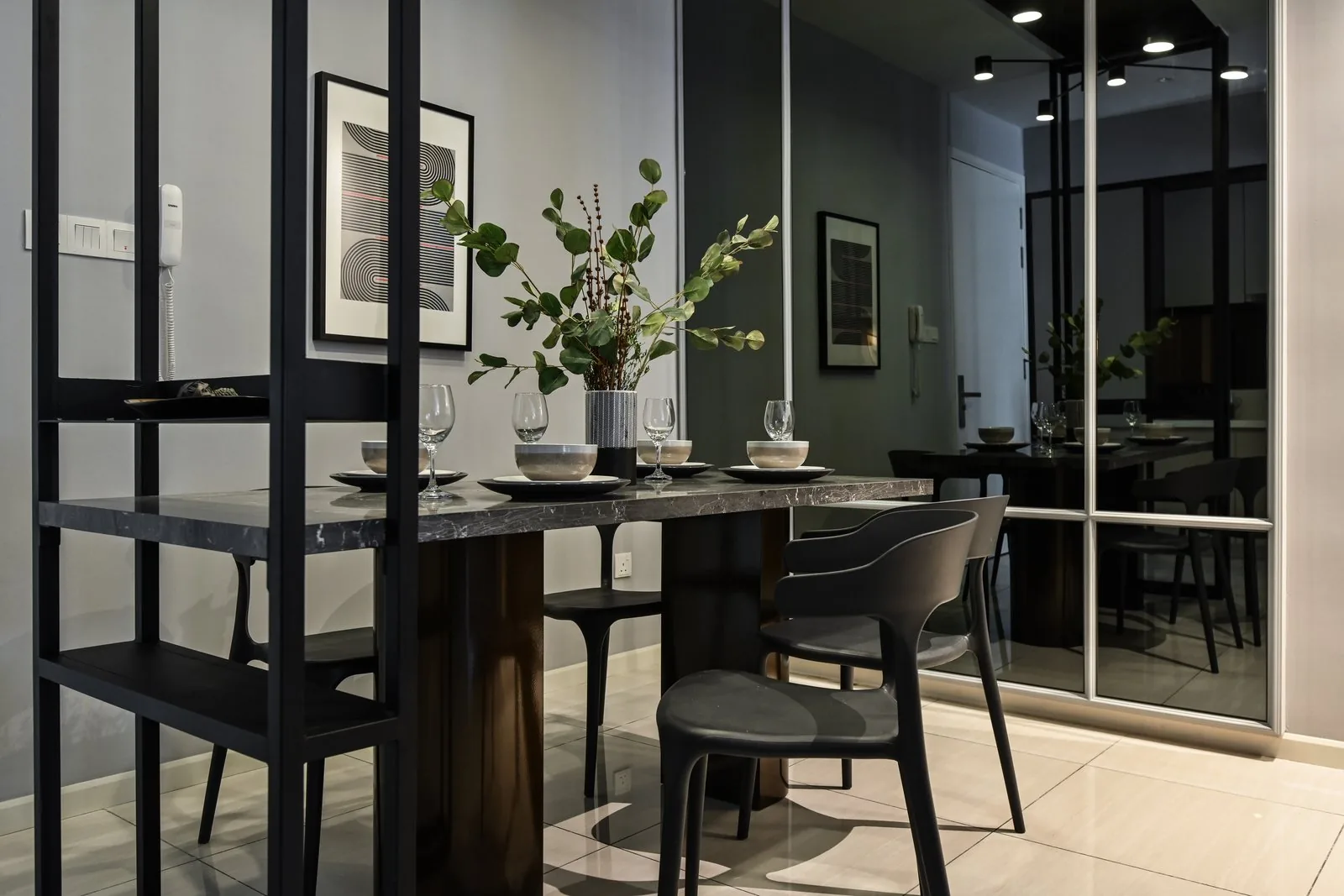 Condo dining area beside a black-framed glass screen and open shelving at the Dorsett Hartamas show unit
