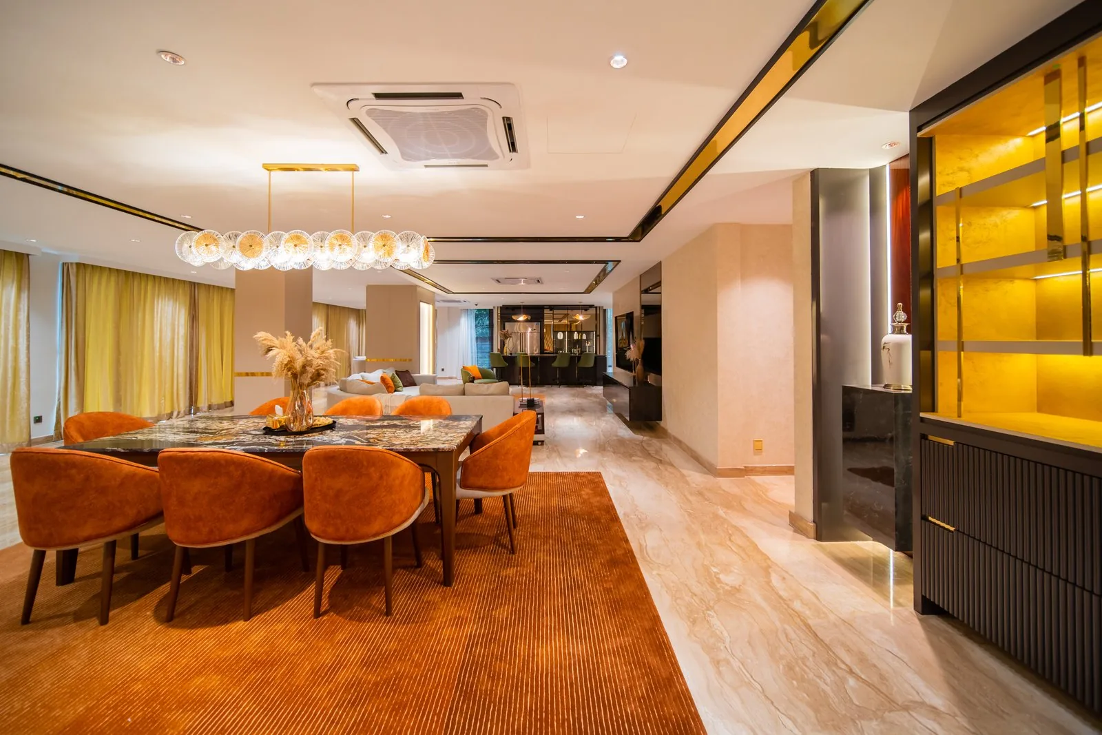 Dining room with a rectangular marble table, orange velvet chairs and a backlit display sideboard in a Bangsar bungalow