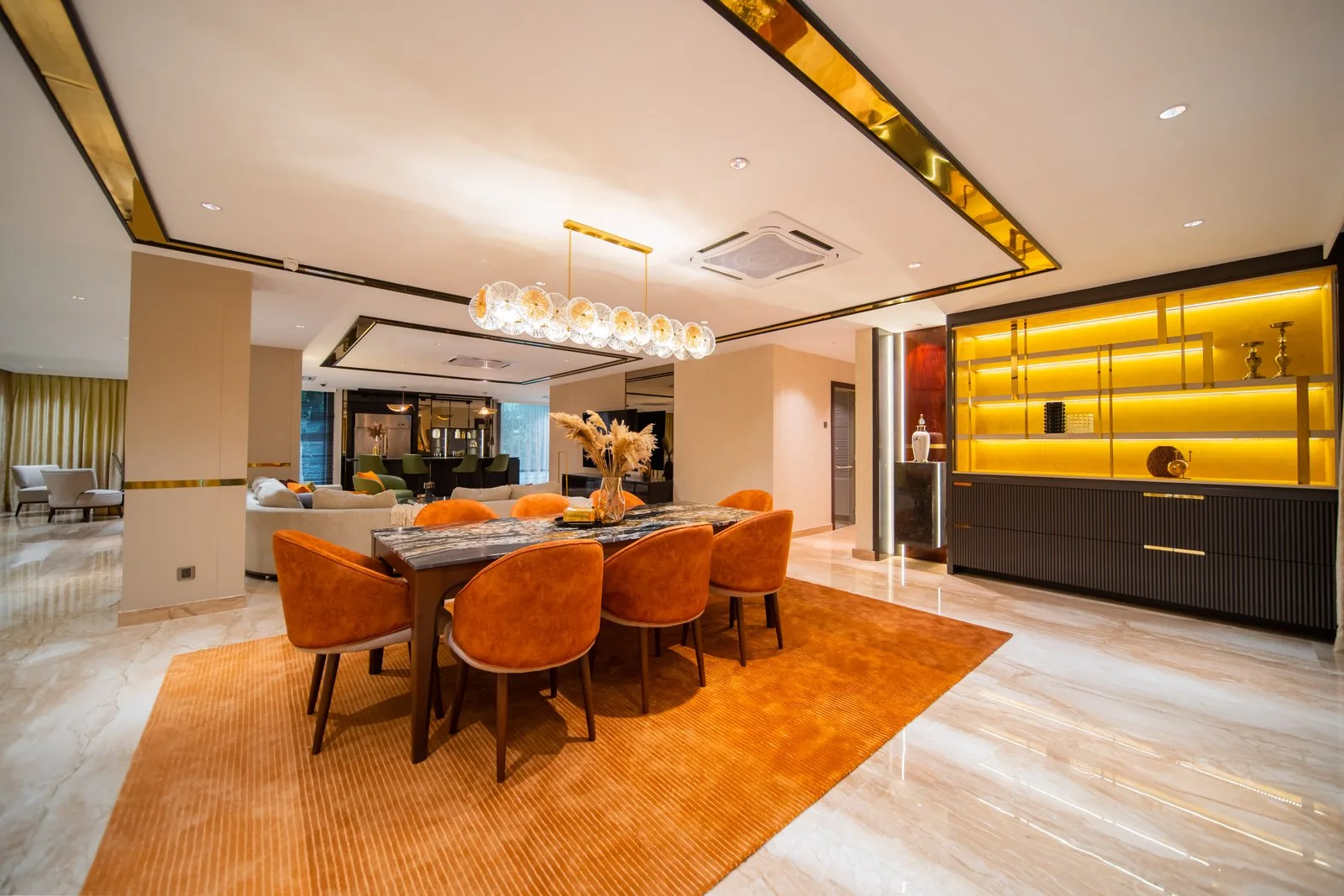 Open-plan dining and living room with orange chairs, a glass chandelier and neutral tones in a Bangsar bungalow