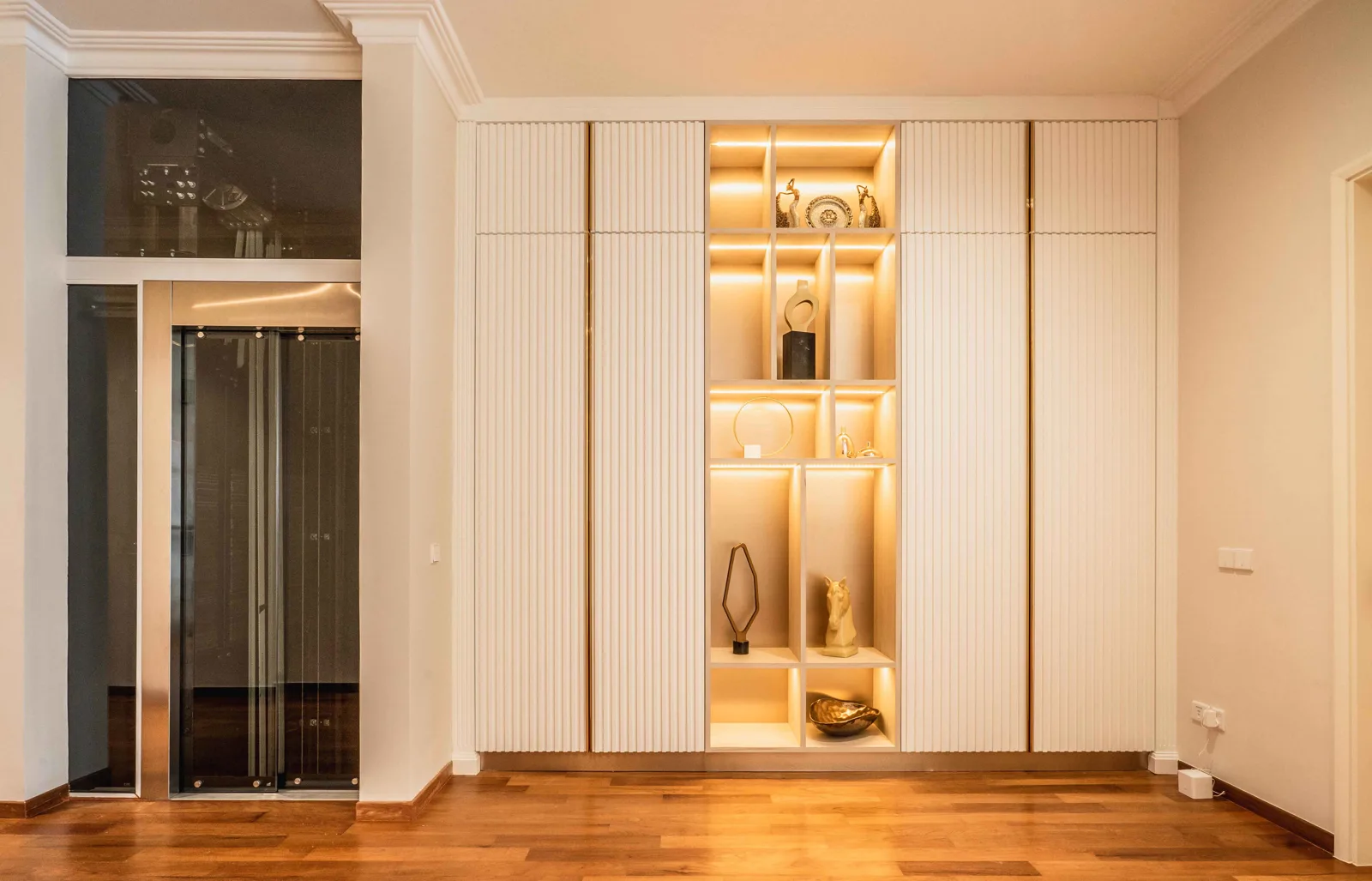 Upper-floor hall with a home lift and full-height built-in cabinets with lit display niches, EcoSpring Villa