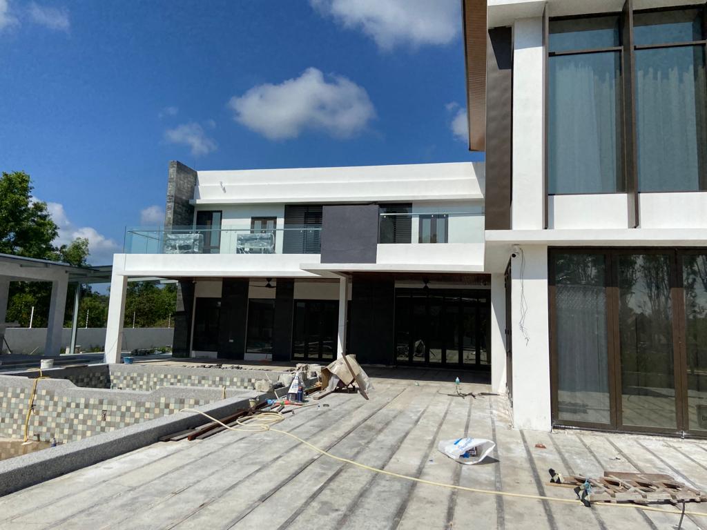 Modern two-story residence under construction with large windows, balcony, and an unfinished pool area.