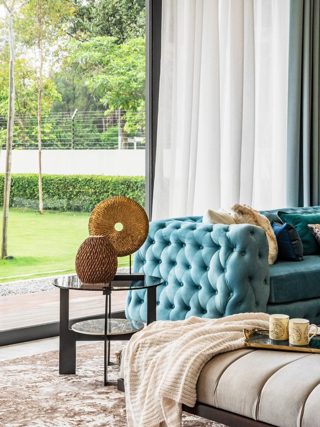 Daybed with knit throw beside the teal sofa in a Kelana Jaya bungalow living hall, overlooking the garden.