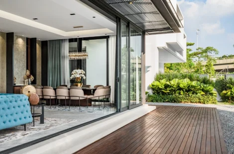 Living hall opening fully to the timber deck and garden of a Kelana Jaya bungalow through retracted sliding doors.