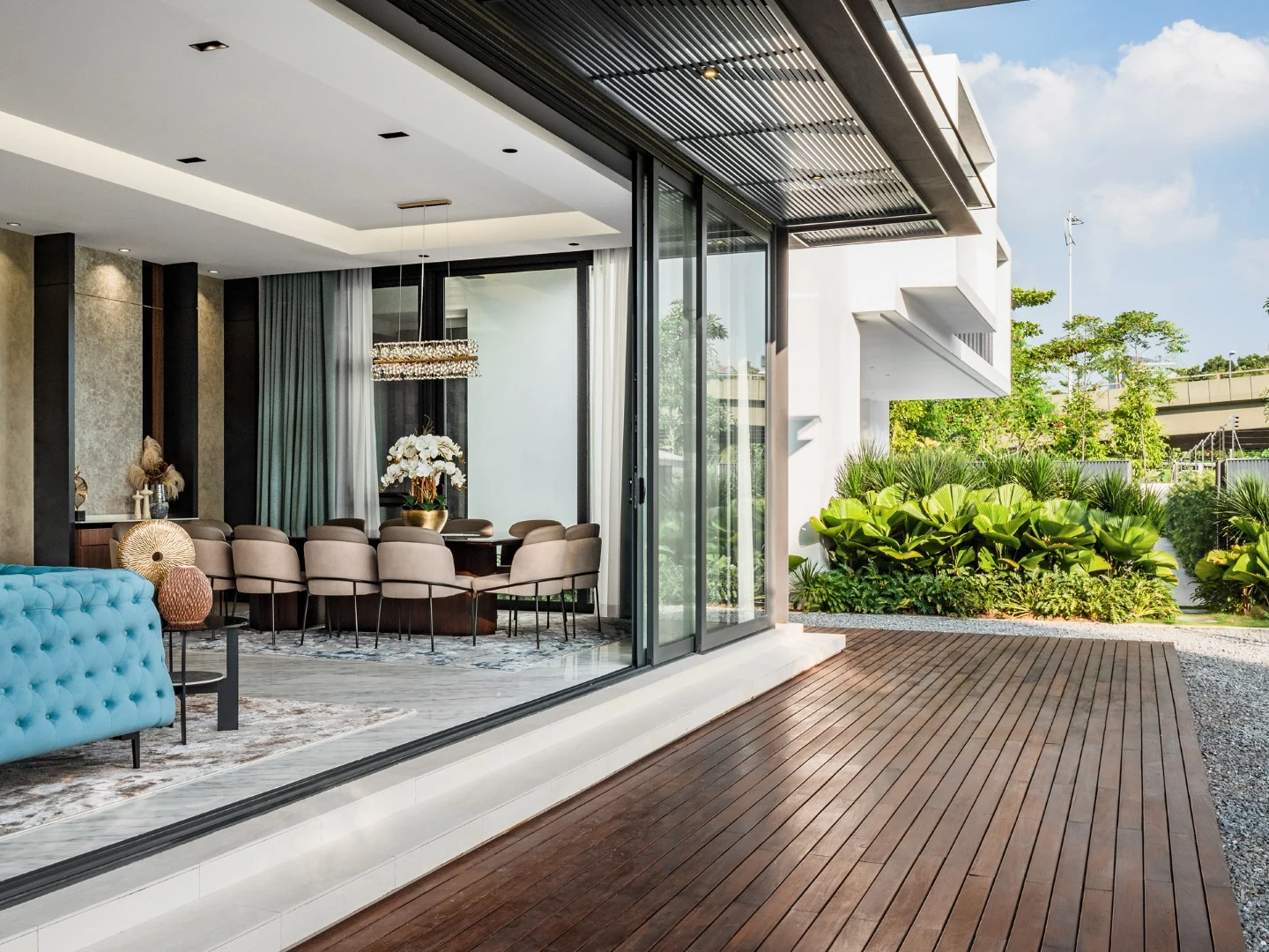 Living hall opening fully to the timber deck and garden of a Kelana Jaya bungalow through retracted sliding doors.