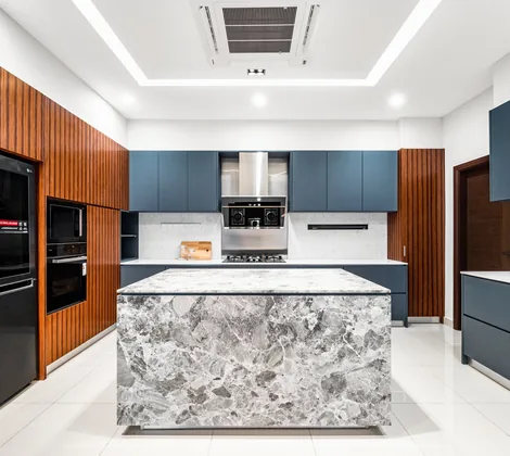 Kitchen cabinet design with navy cabinets, a timber-slatted tall wall and a grey stone island in a Terengganu bungalow by Blaine Robert Design