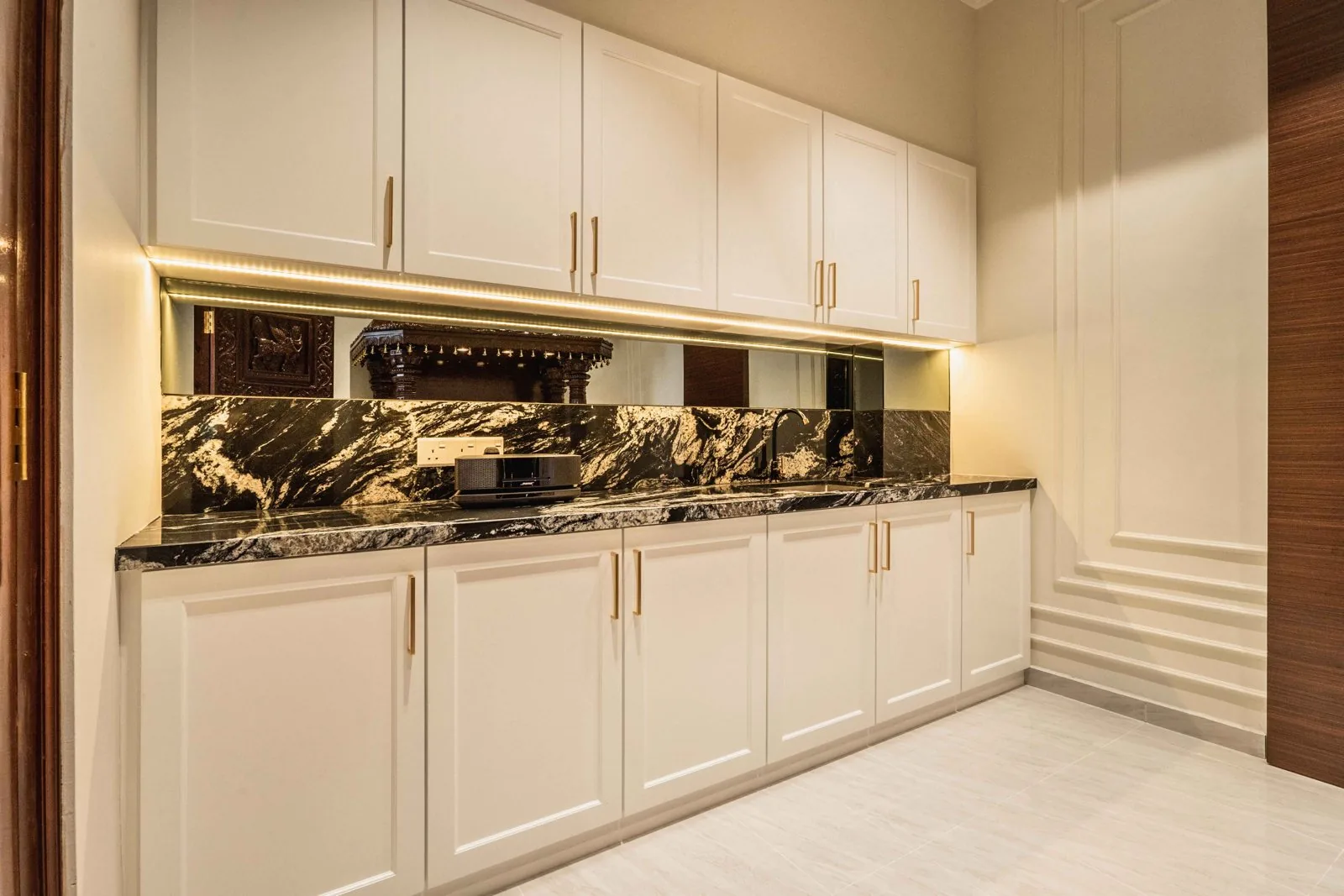 White Shaker kitchen cabinets with slim gold handles under a black marble backsplash at EcoSpring Villa, Johor Bahru