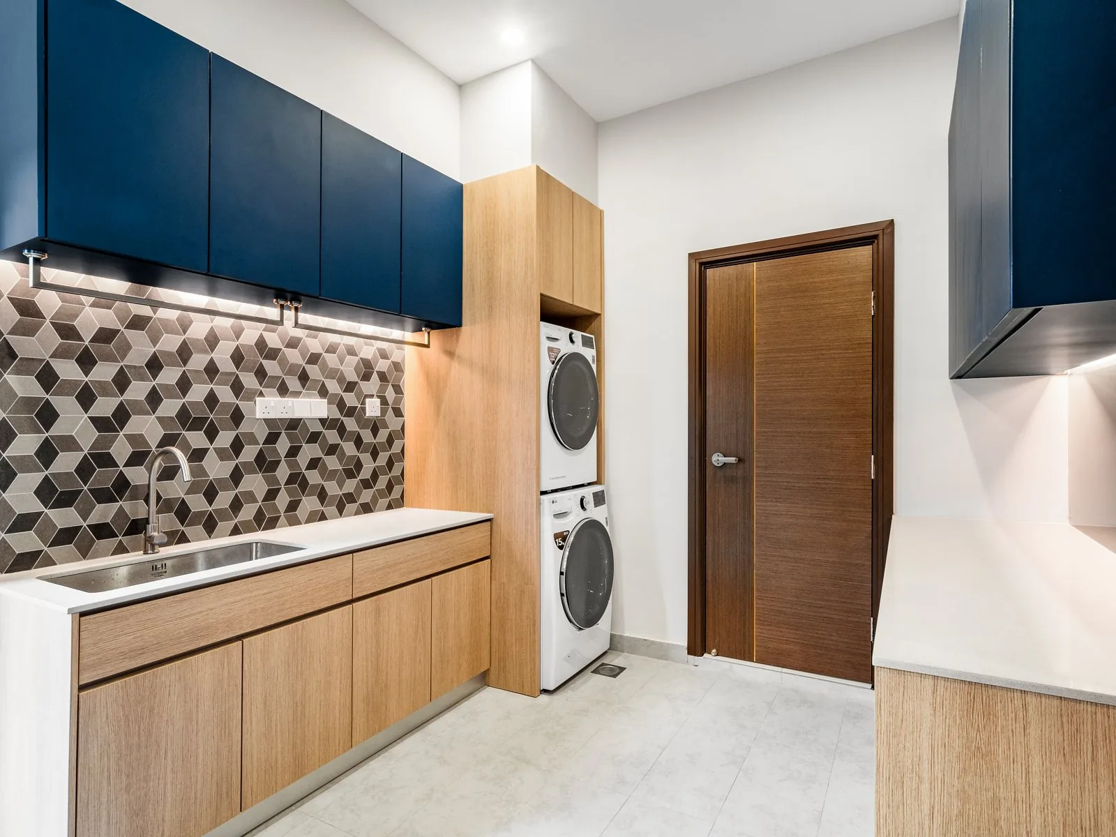Two-tone wet kitchen cabinets with navy wall units over oak-finish base units and a stacked washer and dryer, Terengganu bungalow