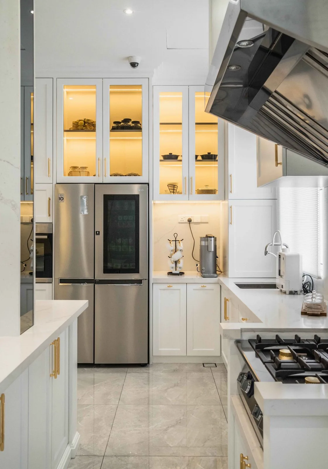 Glass-front kitchen wall cabinets lit from inside above white Shaker base cabinets at EcoSpring Villa