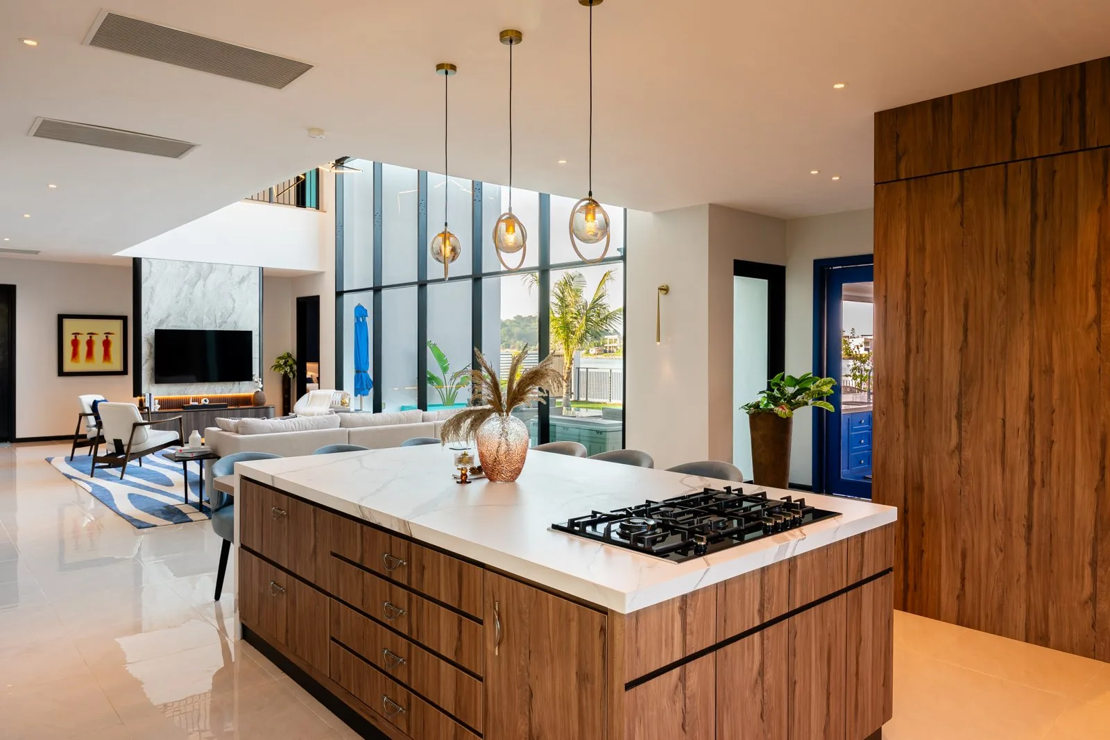Timber kitchen island with deep drawers and a gas hob in front of a tall timber cabinet wall at Quayside Villa