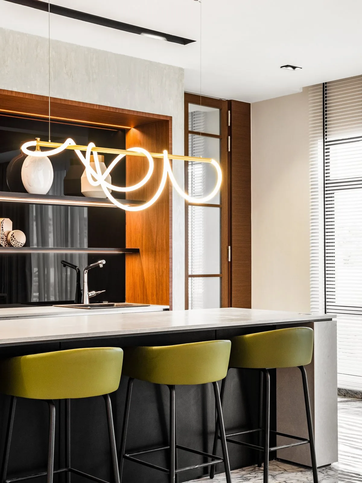 Backlit open niche shelving behind a bar counter with green stools in a Terengganu bungalow