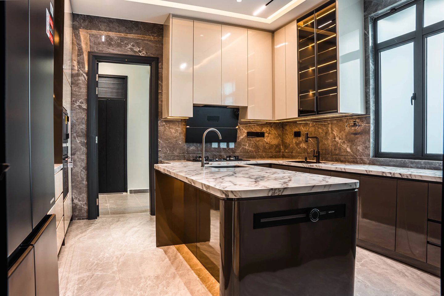 Dry kitchen with marble-topped island, dark gloss cabinetry and integrated appliances at Setia Marina One, Cyberjaya, by Blaine Robert Design