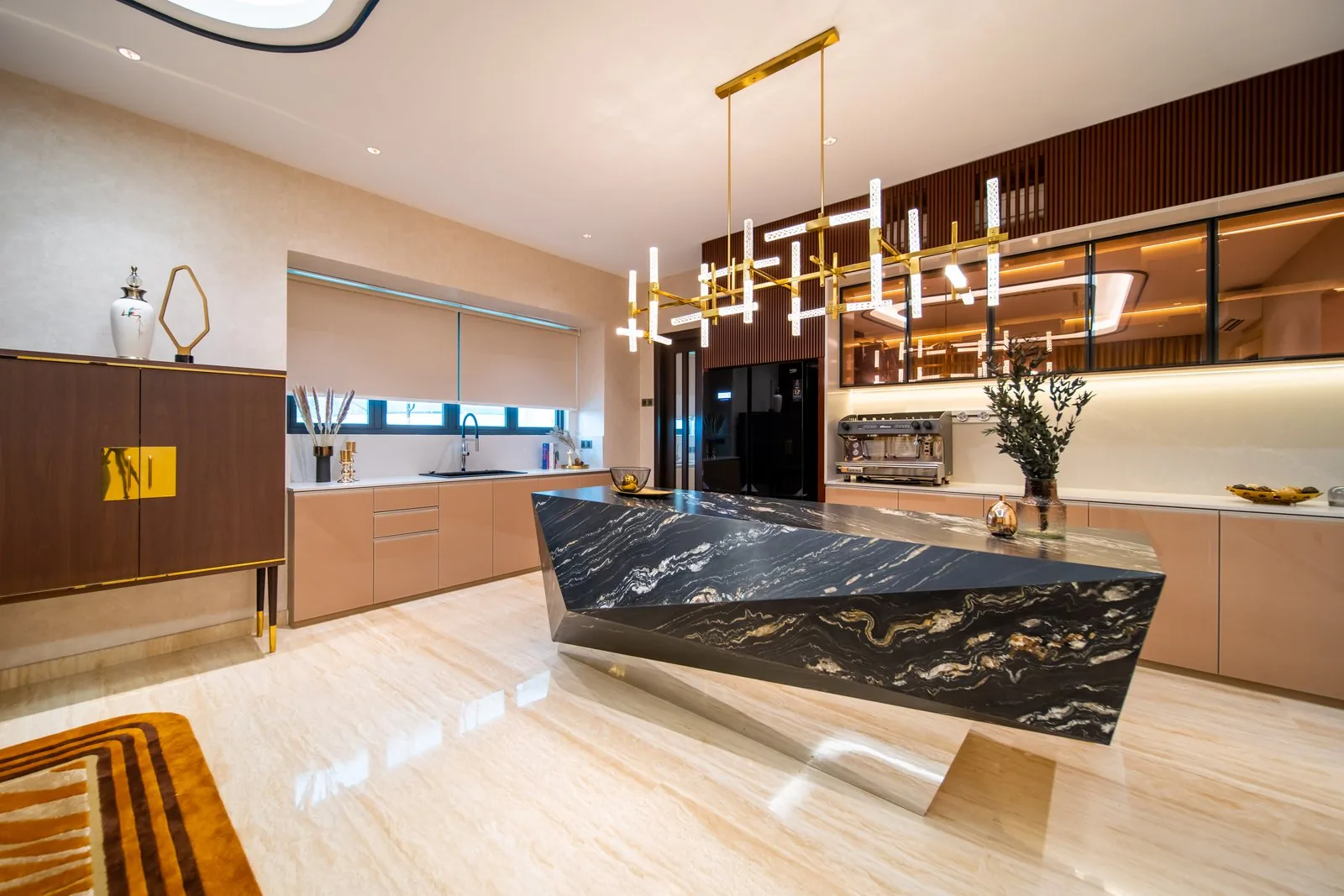 Kitchen island design with a black stone waterfall edge under a linear brass chandelier in a Bangsar bungalow, Kuala Lumpur
