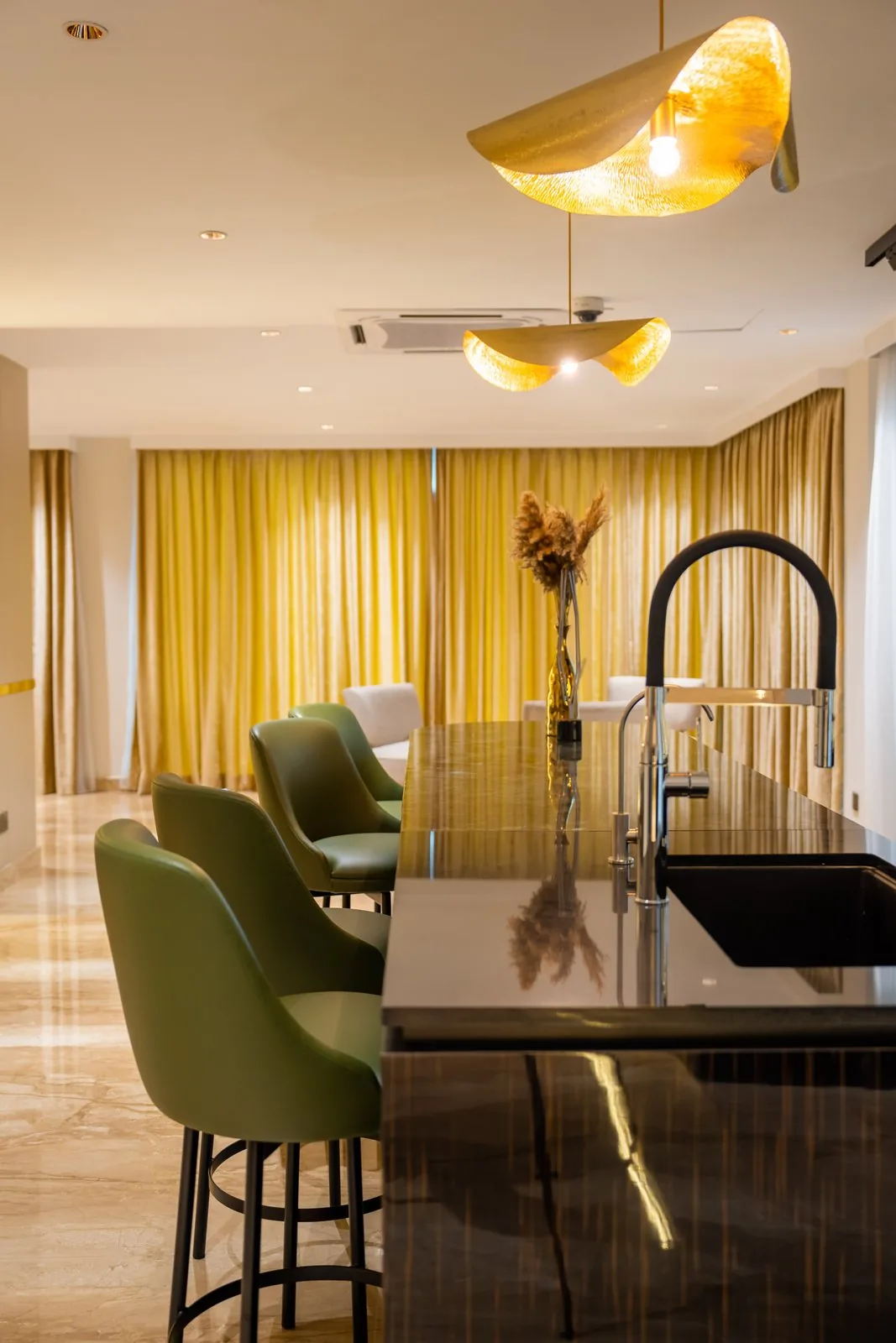 Kitchen island with a prep sink and pull-down tap beside olive bar stools in a Bangsar bungalow
