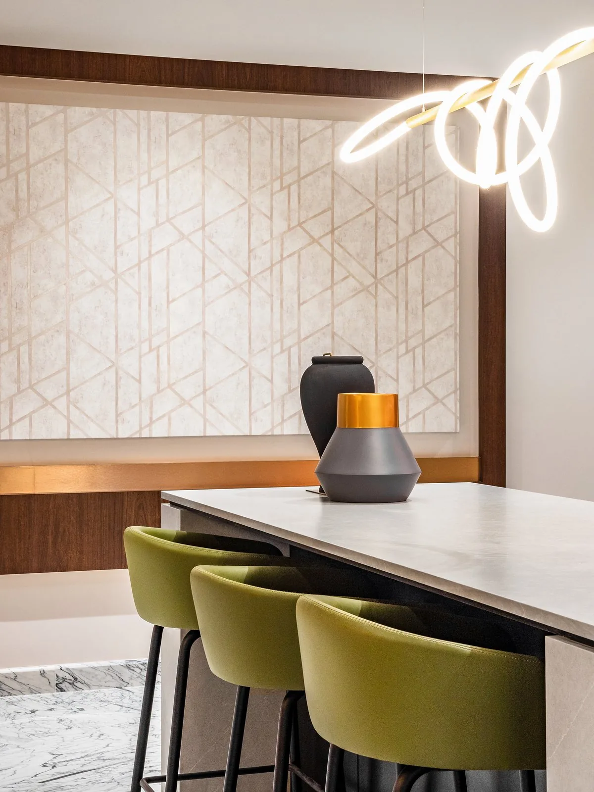 Olive bar stools at a kitchen island under a sculptural LED pendant at East Coast Villa
