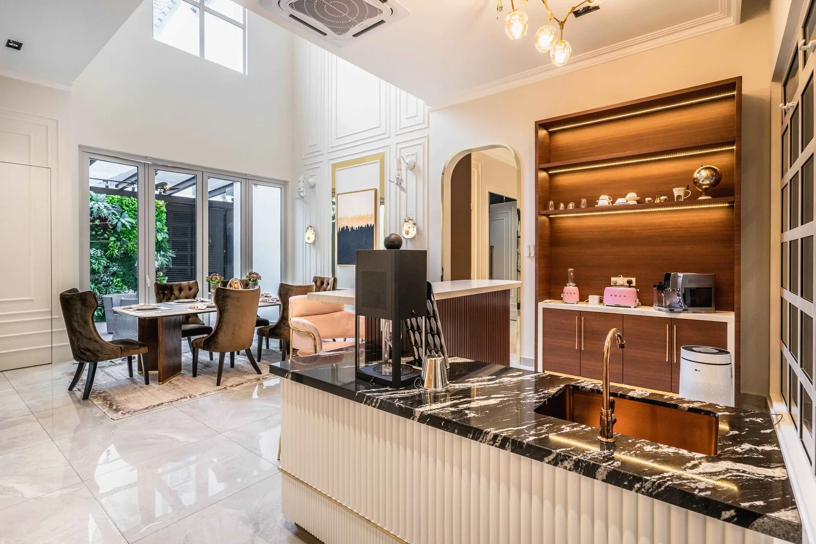 Two-tier kitchen island with a fluted base and black marble top facing the dining area at EcoSpring Villa