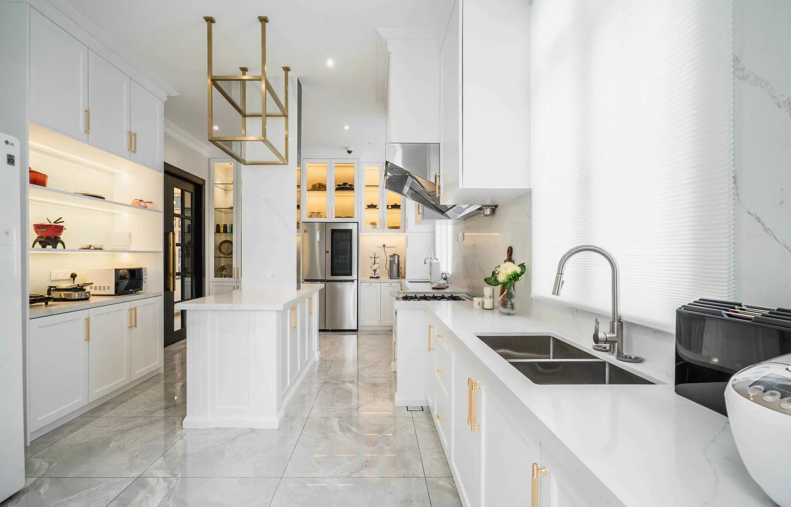 Galley kitchen with a white island and brass hanging rack at EcoSpring Villa, Johor Bahru