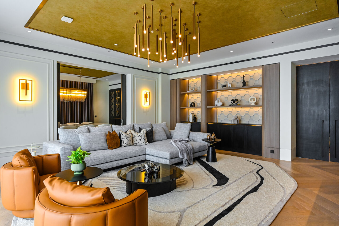 Layered lighting in a condo living room — chandelier, backlit shelving and wall sconces