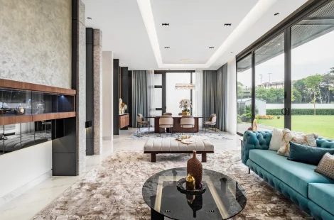 Large patterned rug anchoring a teal chesterfield sofa, bench and armchairs in a living room with garden view, Kelana Jaya bungalow