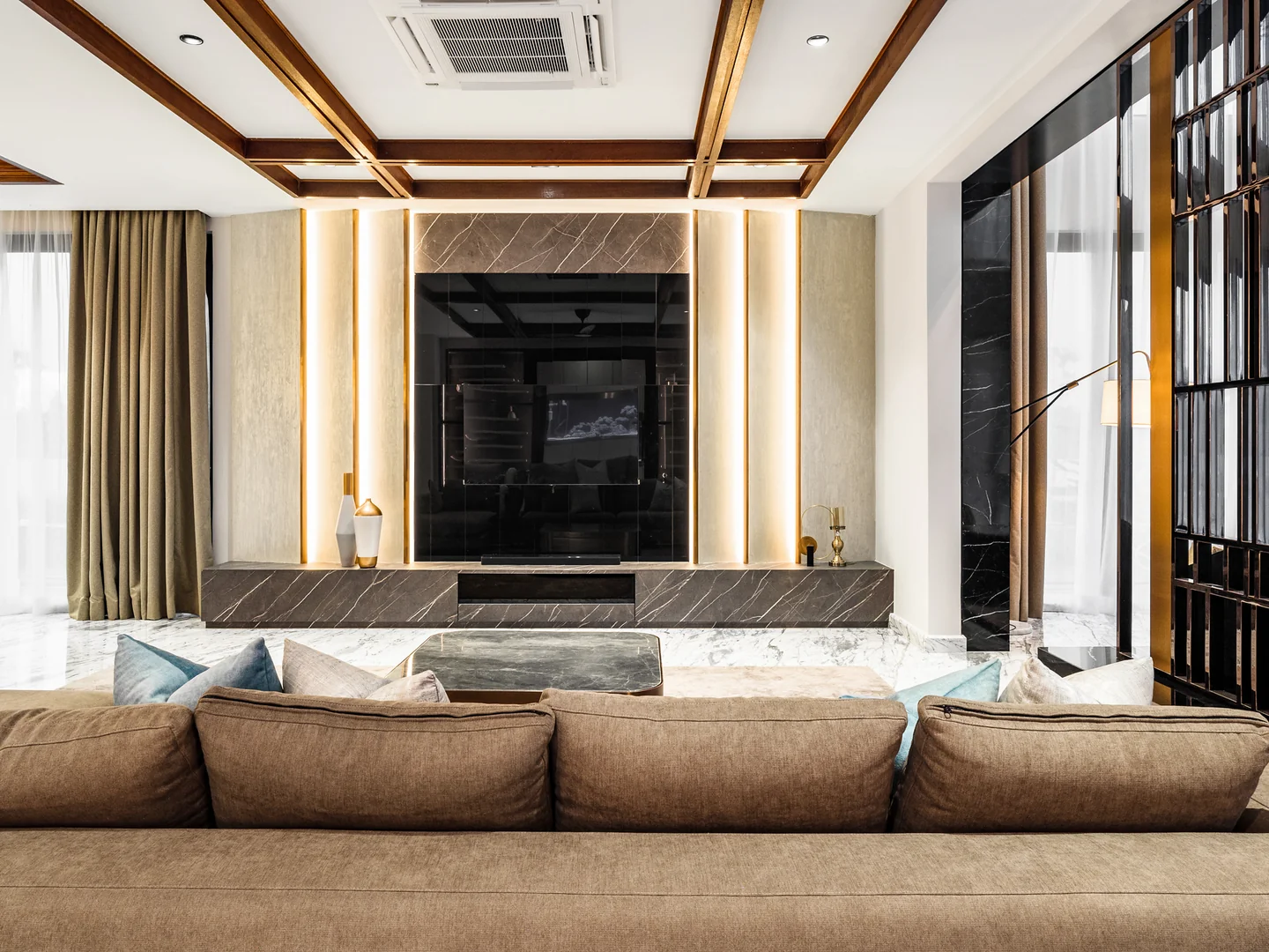 Living room focal point: black marble television wall with recessed lighting behind a brown sectional, Malaysian bungalow