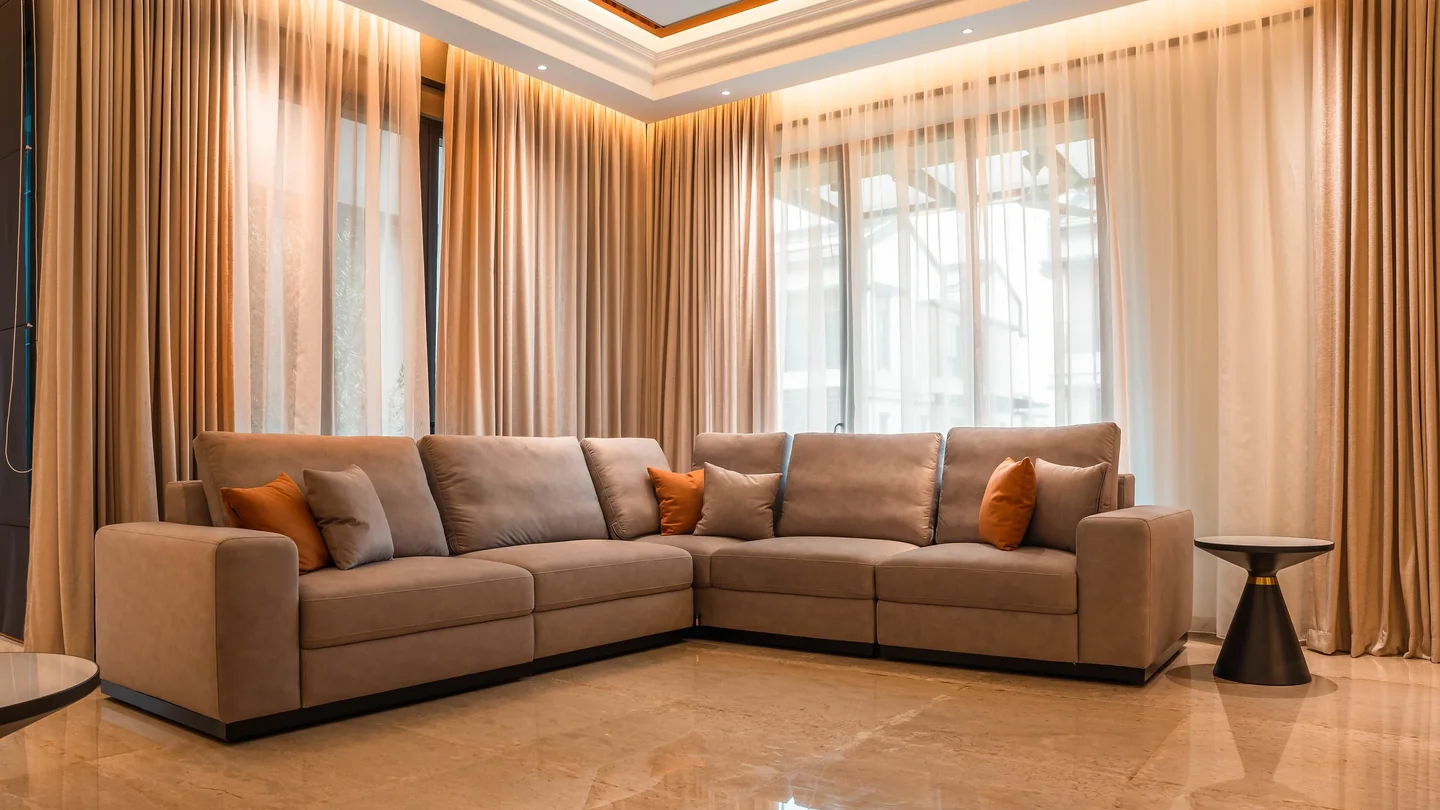 Living room with floor-to-ceiling sheer curtains diffusing daylight over a beige sectional sofa, Setia Marina One bungalow