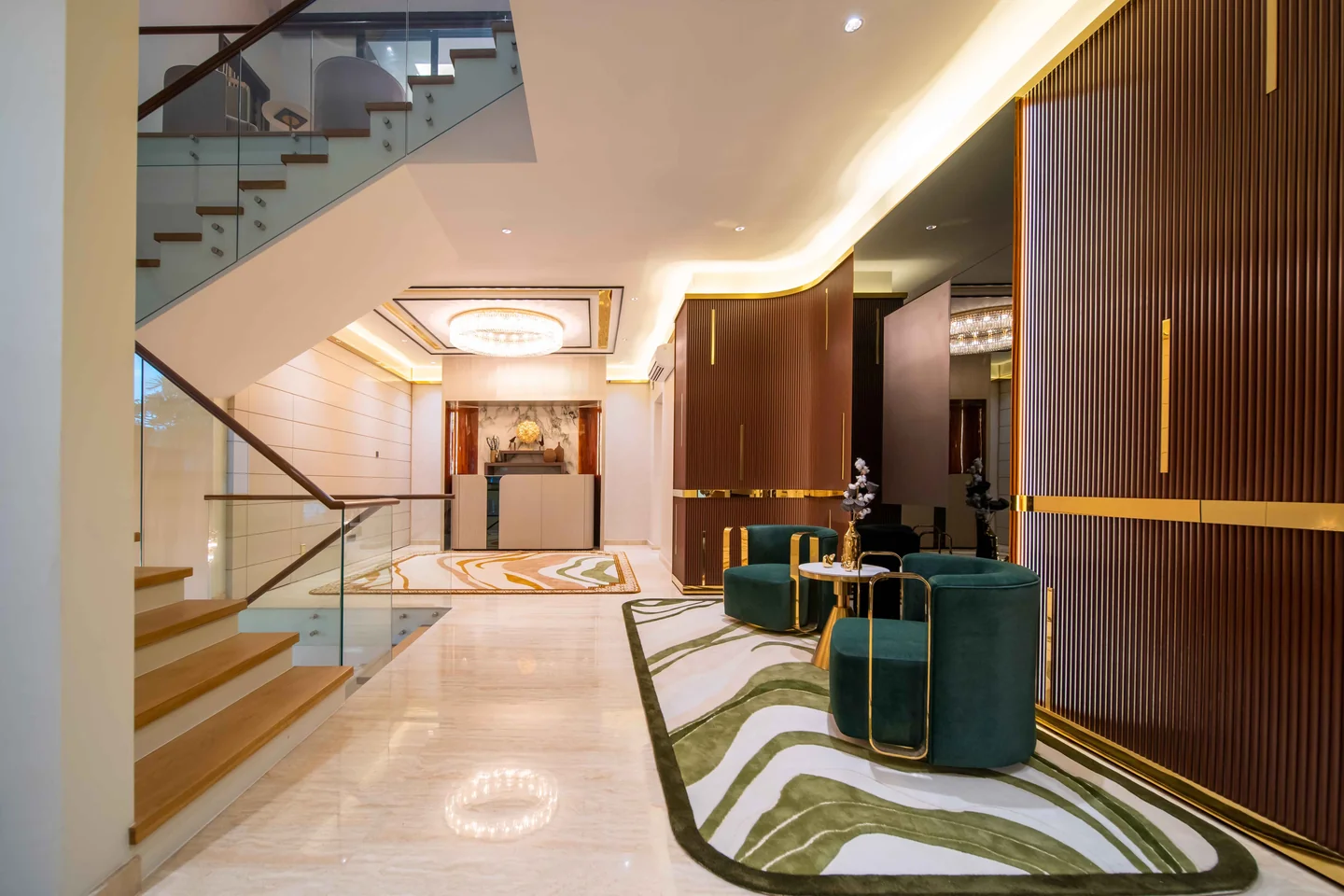 Dramatic lighting in a double-height foyer with lit staircase, marble console and green velvet stools, Bangsar Bukit Pantai bungalow