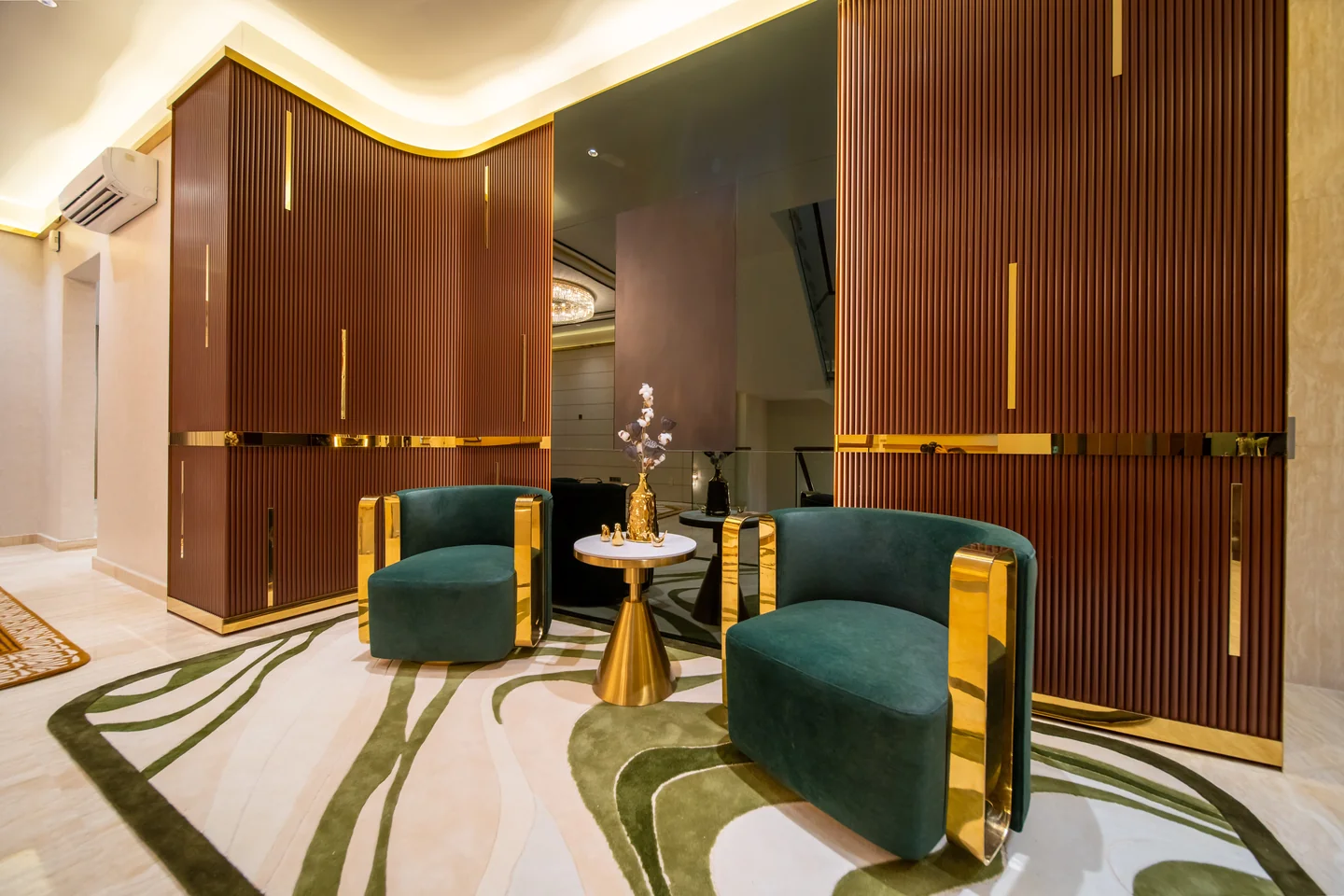 Emerald green velvet armchairs with brass legs beside a fluted walnut and brass feature wall, Bangsar Bukit Pantai bungalow