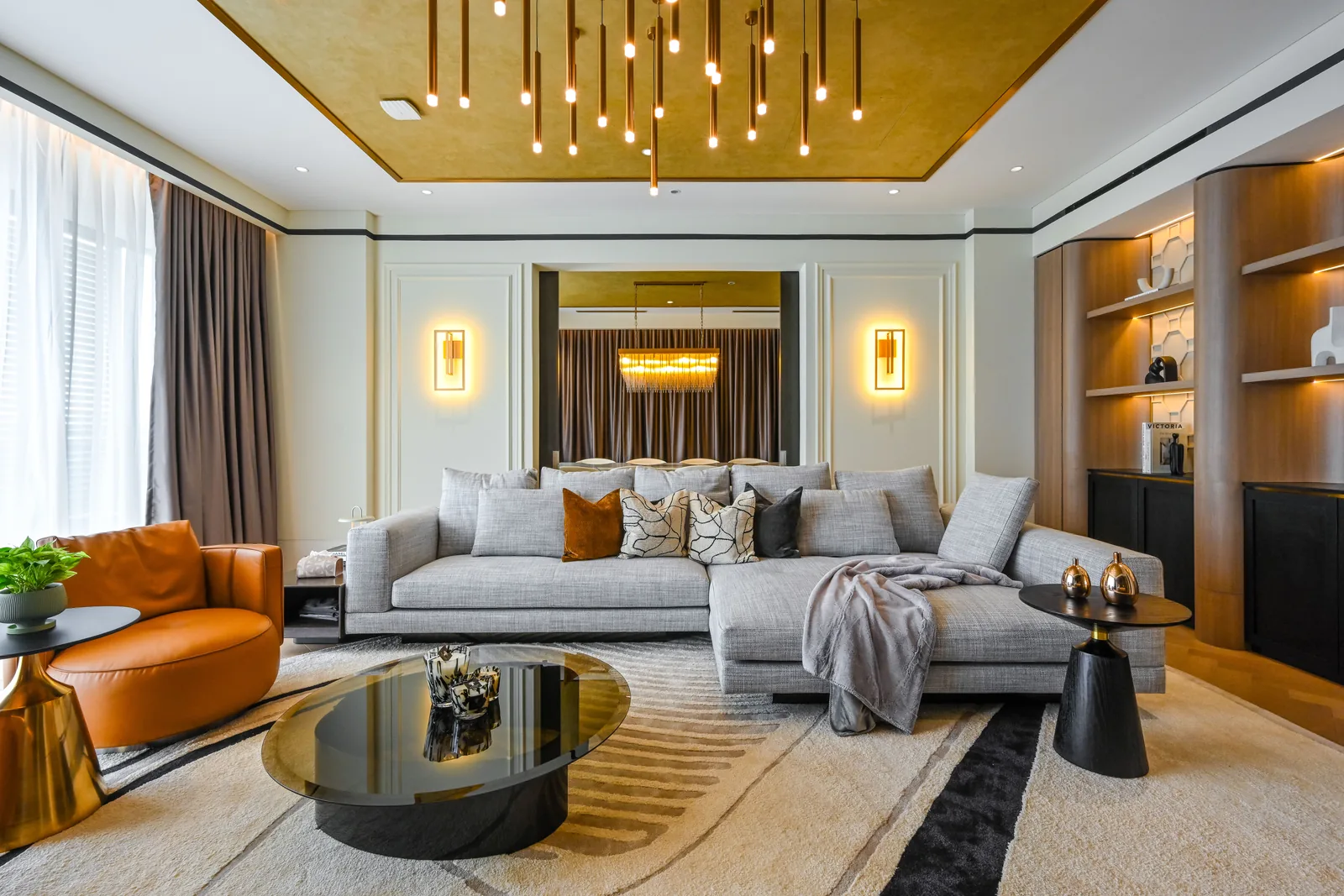Modern contemporary interior design in Malaysia — warm-neutral living room with a curved leather chair, backlit shelving and a gold-leaf ceiling at Aira Residence, Damansara Heights, by Blaine Robert Design