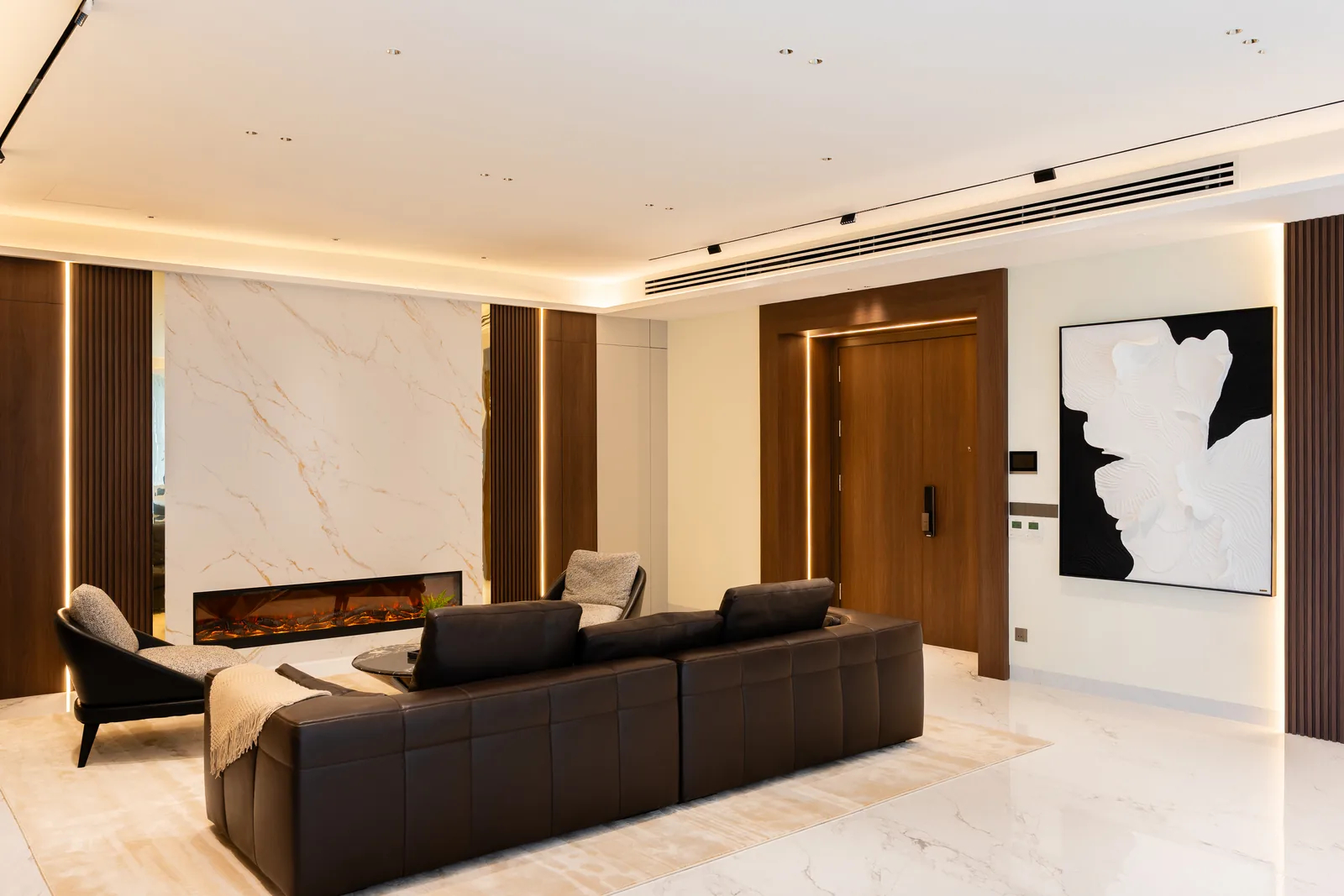 Modern contemporary living room with a book-matched marble wall, walnut panels and a leather sofa at Park Regent, Desa ParkCity