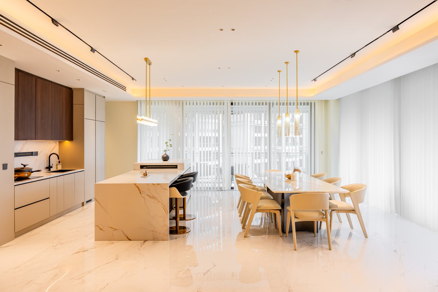 One-wall kitchen with white cabinets and a marble-topped island with bar seating in a Kuala Lumpur condominium, designed by Blaine Robert Design