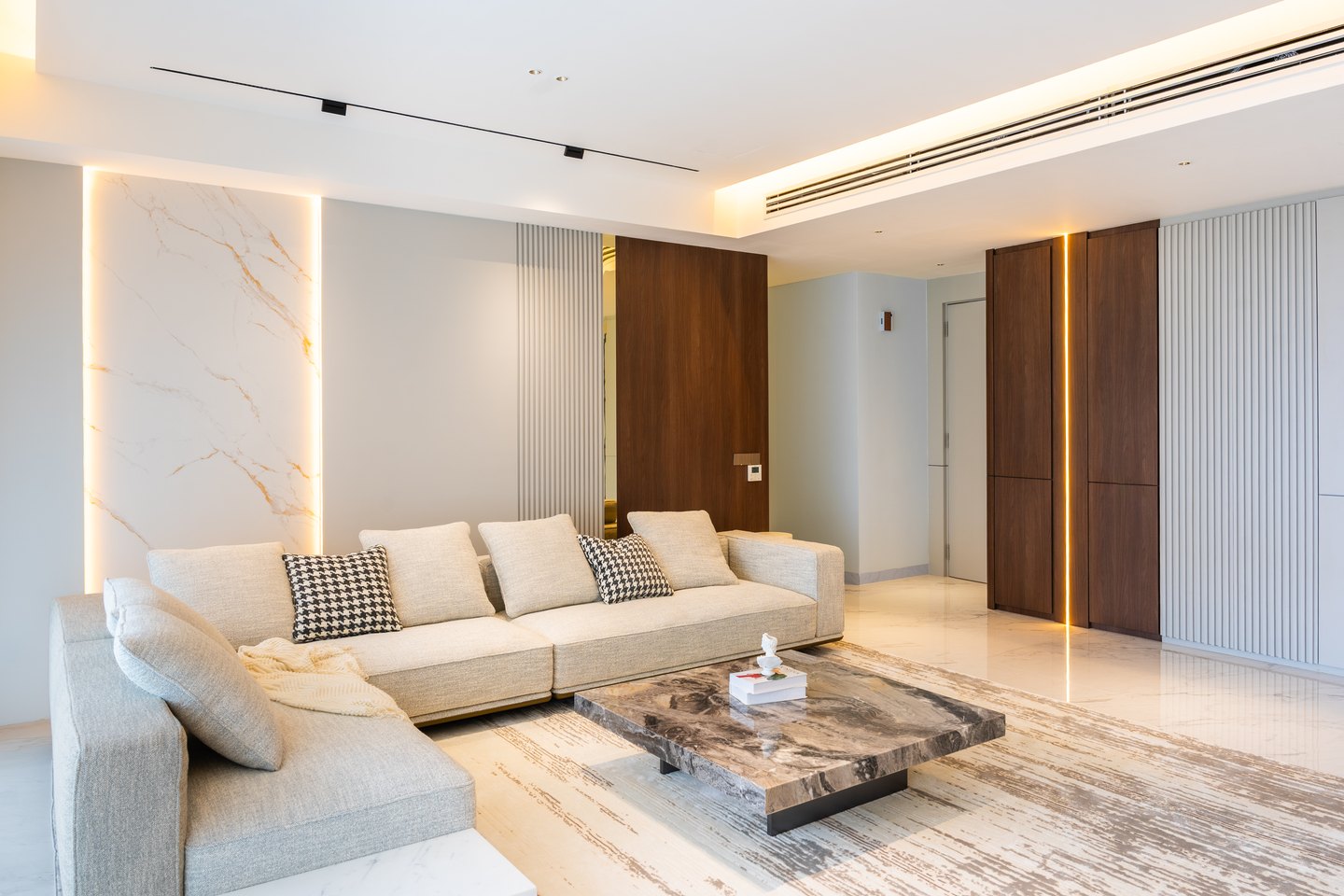 Minimalist living room with backlit marble wall panel and timber flutes at Park Regent, Desa ParkCity