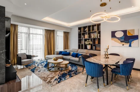 Open-plan living hall of a high-rise residence at the Ritz-Carlton Residences, Kuala Lumpur — sectional, dining table and display shelving in one footprint.