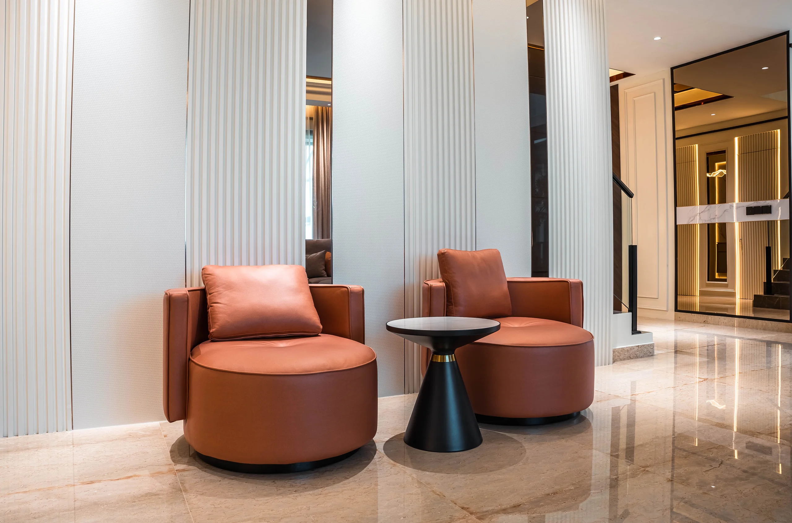 Terracotta swivel armchairs against fluted panelling with mirror inlays at Setia Marina One, Cyberjaya.