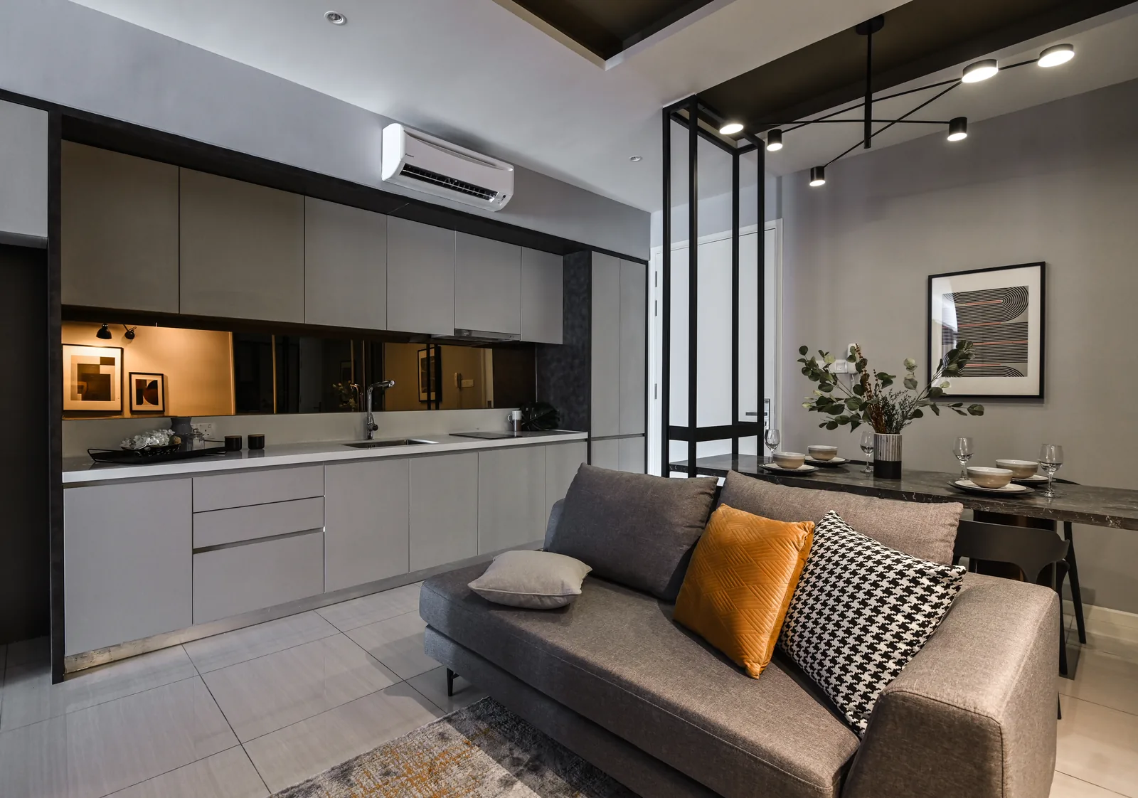 Small kitchen design in a Sri Hartamas condo: a one wall kitchen with grey flat panel cabinets, a smoked mirror backsplash and a dining table beside it, by Blaine Robert Design
