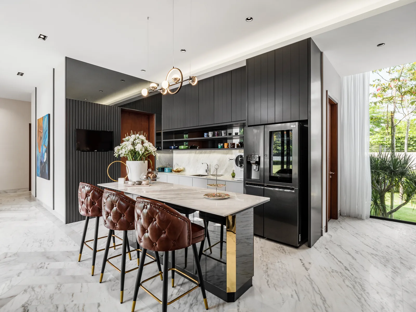 Kitchen with a marble breakfast bar, tufted leather stools and dark cabinets in the Kelana Jaya Villa