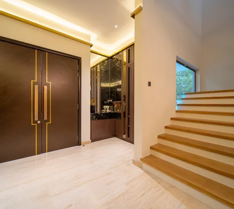 Wide timber stair treads rising beside double entrance doors in the entrance hall of a Bangsar bungalow by Blaine Robert Design