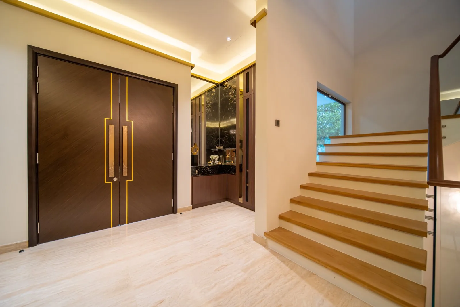 Wide timber stair treads rising beside double entrance doors in the entrance hall of a Bangsar bungalow by Blaine Robert Design